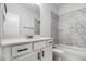 Modern bathroom features gray tile accents, a white vanity, updated fixtures and hardware, and tub with shower at 301 Retreat Way, Carrollton, GA 30116