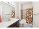 Bathroom with a granite counter top, bright multicolored shower curtain, and neutral colored tile flooring at 6415 Yellow Birch St, Cumming, GA 30040