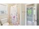 Bathroom features a toilet next to a shower with a floral shower curtain and a window at 6415 Yellow Birch St, Cumming, GA 30040