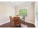 Charming dining area featuring a round wooden table and four chairs bathed in natural light from a large window at 6415 Yellow Birch St, Cumming, GA 30040