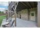 View of the lower level patio featuring concrete flooring, brick supports, outdoor seating, and stairs to the deck above at 6415 Yellow Birch St, Cumming, GA 30040
