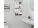 Bright bathroom featuring a pedestal sink, framed artwork, oval mirror, and natural light from a window at 2395 Saint James Nw Dr, Atlanta, GA 30318