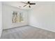 This bedroom has neutral carpet, white walls and trim, a ceiling fan, and a window overlooking a treed landscape at 2395 Saint James Nw Dr, Atlanta, GA 30318