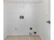 The laundry room features white walls and tile floors, equipped with essential hookups and shelving for convenience at 2395 Saint James Nw Dr, Atlanta, GA 30318