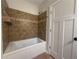 Bathroom featuring a tub with tiled walls and updated flooring, a neutral color palette, and a white door at 1647 Walker Ave, Atlanta, GA 30337