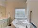Bathroom featuring a soaking tub with tile surround, a window, and a white tile floor at 658 Eight Point Ct, Suwanee, GA 30024
