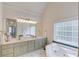 Bathroom featuring a soaking tub, dual sink vanity, framed mirror, and bright natural light at 658 Eight Point Ct, Suwanee, GA 30024