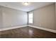 Cozy bedroom featuring hardwood floors, neutral paint, and natural light from a window at 11760 Stratham Dr, Alpharetta, GA 30009