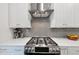 Close-up of stainless steel gas range, gray subway tile backsplash, and white cabinets, offering modern elegance at 4311 Parkside Pl, Atlanta, GA 30342