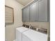 Efficient laundry room includes white washer and dryer, grey cabinets, and a wall-mounted drying rack at 4311 Parkside Pl, Atlanta, GA 30342