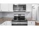 Close-up of a range and microwave nestled between granite countertops and white cabinets, creating a sleek and practical kitchen at 1718 Cahoon Sw St, Atlanta, GA 30310