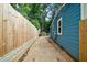 View of a narrow side yard featuring a wood fence, concrete walkway and the blue siding of the house at 1718 Cahoon Sw St, Atlanta, GA 30310