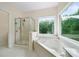 Relaxing bathroom featuring a separate shower and soaking tub with a window overlooking lush greenery at 207 Breckenridge Ct, Canton, GA 30115