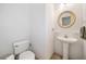 Stylish half bathroom with a pedestal sink, round mirror, and clean white walls at 207 Breckenridge Ct, Canton, GA 30115