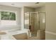 Bright bathroom offers a separate glass door shower and a soaking tub near a large window at 180 Jay Trl, Fayetteville, GA 30215