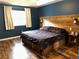 Bedroom featuring a wood accent wall with lighting, drawers under bed and beautiful flooring at 2105 Windy Oak Ct, Lithia Springs, GA 30122