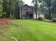 Two-story home with attached garage, lush lawn, and wooden fence bordering a wooded area at 2105 Windy Oak Ct, Lithia Springs, GA 30122