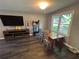 Living room featuring hardwood floors, a large TV, and a dining area near a bright window at 2105 Windy Oak Ct, Lithia Springs, GA 30122