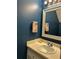 Powder room with dark blue wall and decorative mirror and neutral sink and countertop at 2105 Windy Oak Ct, Lithia Springs, GA 30122