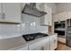 Kitchen featuring stainless steel hood, modern appliances, white tile backsplash, and quartz countertop at 3695 Andover St, Cumming, GA 30028