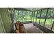Enclosed sunroom with backyard view, wooden floors and vintage style couch at 4055 Haralson Mill Ne Rd, Conyers, GA 30012