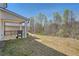 Large backyard with a covered porch, grill, and wooded area beyond the lawn at 1936 Waycross Ln, Dacula, GA 30019