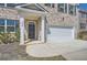 Inviting home entrance featuring a covered porch, stone accents, and a two-car garage at 1936 Waycross Ln, Dacula, GA 30019