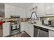 A well-lit kitchen features stainless steel appliances, white cabinets and light countertops at 999 Chestnut Oak Ct, Lawrenceville, GA 30046