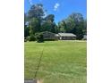 A well-maintained single-story home with a large green yard and mature trees at 3705 Sandhill Se Dr, Conyers, GA 30094