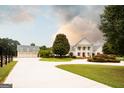 A large white home and detached garage with dormers set on a meticulously landscaped lot at 1875 Highway 142 E, Covington, GA 30014