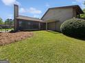 A spacious backyard featuring a covered patio area, lawn, and wooded perimeter in a quiet neighborhood at 1084 Village Rd, Stone Mountain, GA 30088