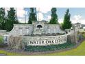 The Water Oak Estates entrance features stone masonry and lush landscaping at 1678 Lacebark Elm Way, Lawrenceville, GA 30045