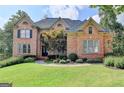 Brick two-story house with a landscaped lawn and mature trees at 2118 Town Manor Ct, Dacula, GA 30019