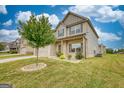 This two-story home is landscaped with a young tree and a mulch bed containing shrubs and flowers at 1223 Hartwell Rd, Locust Grove, GA 30248