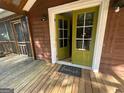 Inviting covered porch with green french doors leading to a wood floor and rug at 171 Knucklesville Rd, Rydal, GA 30171