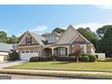 Two-story house with stone and beige siding, a three-car garage, and a landscaped lawn at 348 Relative Trl, Mcdonough, GA 30253