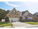 Two-story house with stone and beige siding, a three-car garage, and a landscaped lawn at 348 Relative Trl, Mcdonough, GA 30253