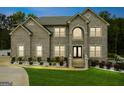 Elegant two-story brick home with landscape lighting and a symmetrical facade at dusk at 3140 Jackson Creek Dr, Stockbridge, GA 30281