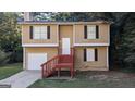 Inviting two-story home featuring tan siding, black shutters, and stairs to a covered front porch at 5300 Forest Downs Ln, Atlanta, GA 30349