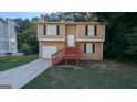 Charming home featuring tan siding, black shutters, a garage, and stairs to a covered front porch at 5300 Forest Downs Ln, Atlanta, GA 30349