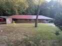 A single-story brick home has a bright red metal roof, a small tree, and a covered carport at 10108 Lakeview Sw Dr, Covington, GA 30014