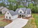 Aerial view of the white farmhouse exterior with a spacious three car garage and long concrete driveway at 241 Ben Horton Dr, Mcdonough, GA 30253
