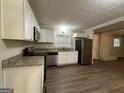 Modern kitchen featuring white cabinets, granite countertops, stainless steel appliances, and wood-look floors at 3086 Meadow Lark Ln, East Point, GA 30344