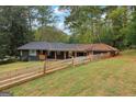 Exterior view of the home surrounded by lush trees and featuring a split-rail fence at 1973 Glendale Dr, Decatur, GA 30032