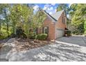 Side view of the brick home featuring a two-car garage and mature landscaping at 7300 Chattahoochee Bluff Dr, Sandy Springs, GA 30350