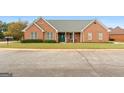 Lovely brick home featuring manicured lawn, green front door, and welcoming front porch at 1115 Oakpark Drive Dr, Mcdonough, GA 30253