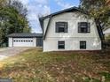 Two-story home with white painted brick, a gray trim, a two-car garage and an attached door on a tree-filled lot at 4239 Newcomb Rd, Decatur, GA 30034