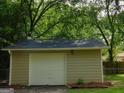 Detached garage with white door and neutral siding in a leafy setting at 99 Libby Ln, Jonesboro, GA 30238