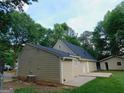 Back of house with a cement patio and green lawn surrounded by mature trees at 99 Libby Ln, Jonesboro, GA 30238