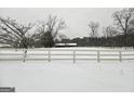 Scenic winter view of property with snow-covered ground and a charming farmhouse in the background at 1024 Bethany Rd, Covington, GA 30016